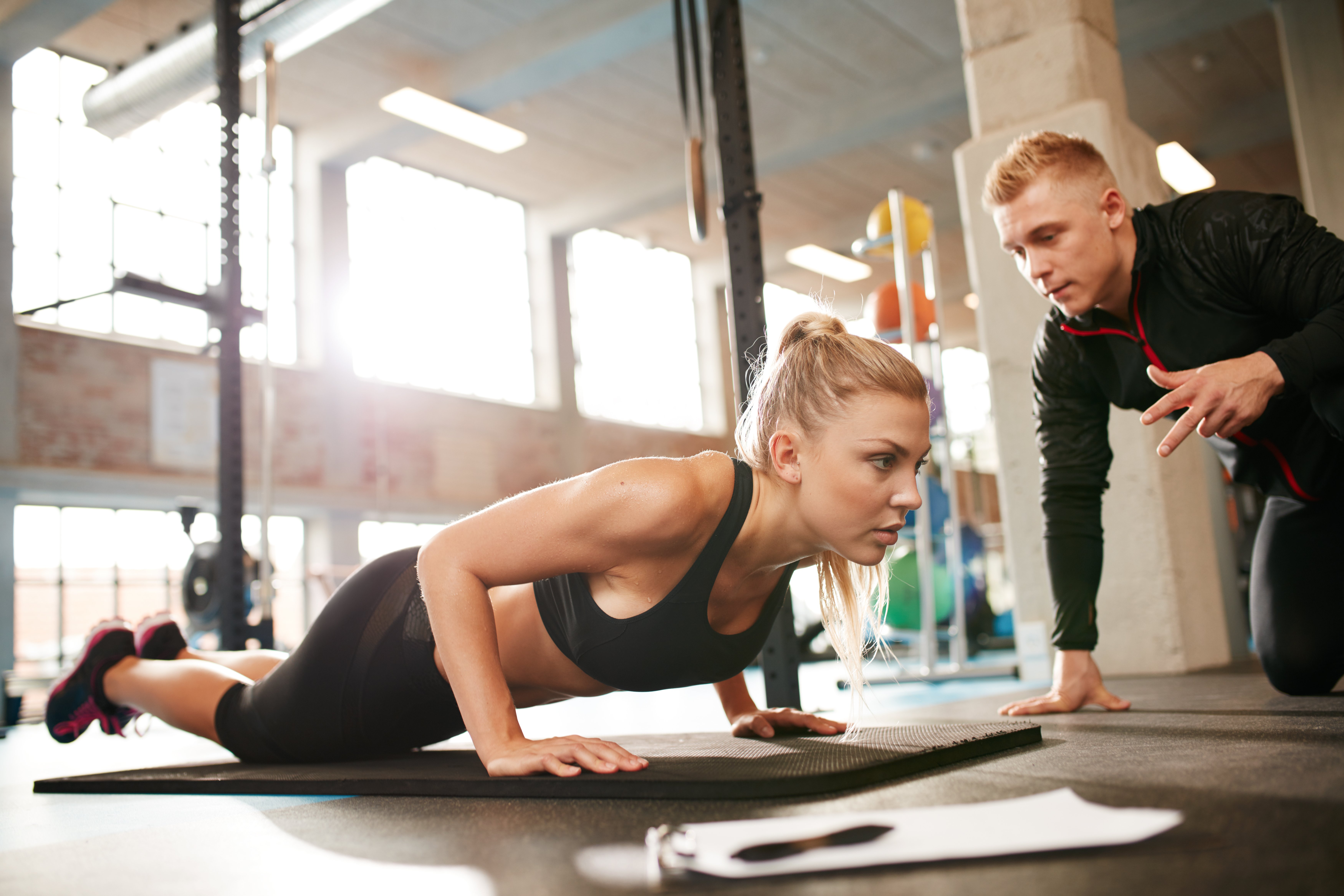 female-exercising-with-personal-trainer-at-gym-PSDYQTU